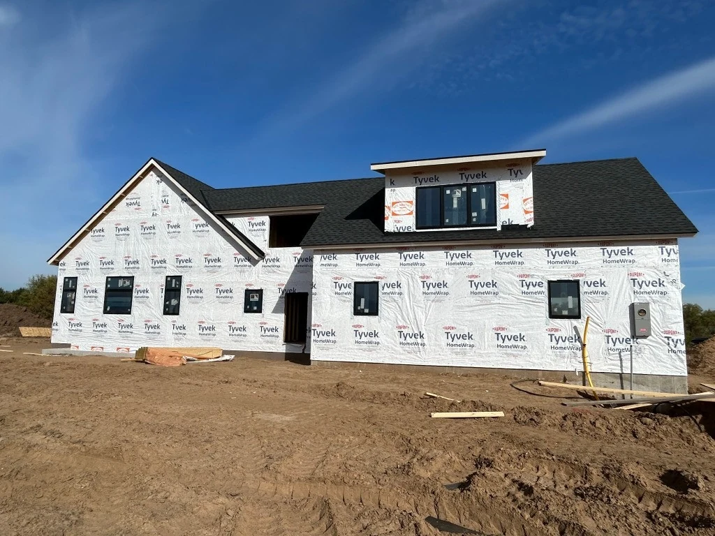A KPS custom home under construction in Afton with roof shingles, house wrap and installed windows