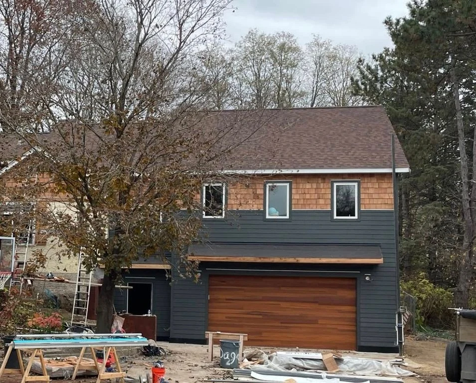 An Arden Hills garage and second-story addition with charcoal siding, cedar shakes and a wood garage door